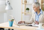 Beautiful cheerful mature woman at office working on computer