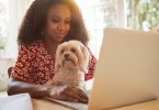 Young woman sitting with her dog and using a laptop