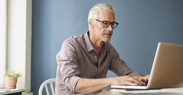 Mature man using laptop on table at home