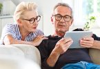 Senior couple watching digital tablet together at home