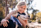 Affectionate mature woman embracing pet dog in nature