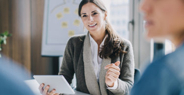 Businesswoman working with tablet while coaching a couple.