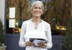 mature woman small business owner outside her restaurant with menus