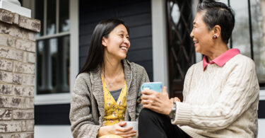 Adult woman and senior mother talking on front porch