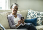 Senior woman using smartphone in living room of suburban home