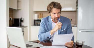 Man using calculator while going through bills and home finances