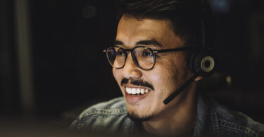 Smiling young male customer service employee wearing headset working at call center