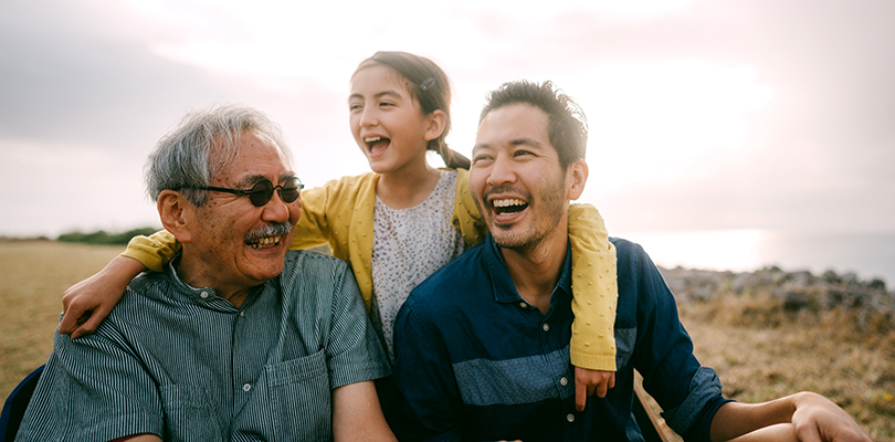 Young girl having fun with her grandfather and father by sea at sunset, Japan
