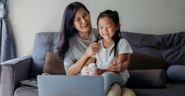 Image of an Asian grandmother with her granddaughter video calling doctor from home with a laptop. Telemedicine and new normal during covid-19 pandemic.