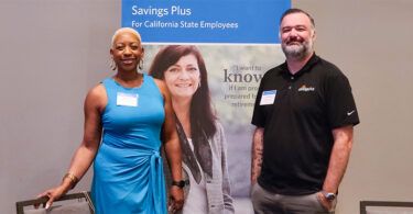 A woman (left) and man (right) in front of a Savings Plus promotional banner.