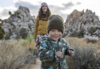 A happy young boy and his mother hiking a trail in the desert.
