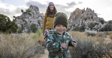 A happy young boy and his mother hiking a trail in the desert.