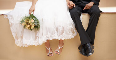 Bride and groom sitting on wall