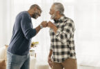 Two older Black men fist-bumping each other.