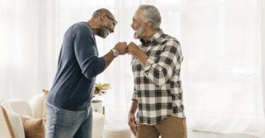 Two older Black men fist-bumping each other.