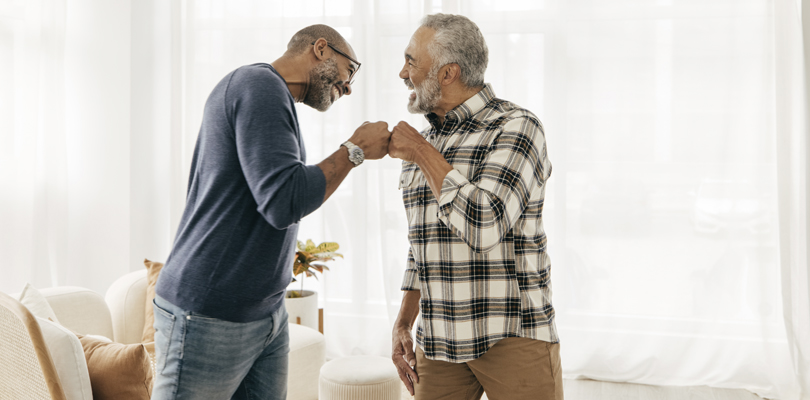 Two older Black men fist-bumping each other.