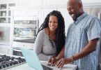 Man and woman using laptop in kitchen at home