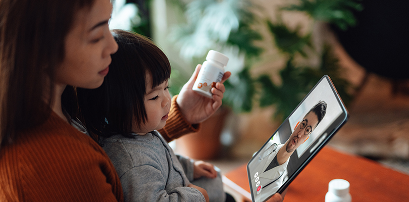 Young Asian mother and child having online medical consultation with doctor on video call