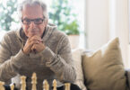 Older man sitting on sofa looking at chess board