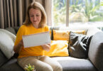 Woman sitting on couch writing in a notebook