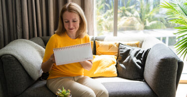 Woman sitting on couch writing in a notebook