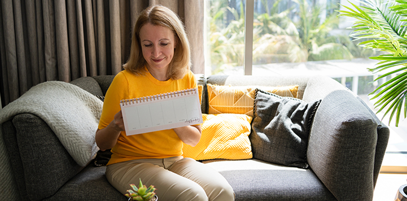 Woman sitting on couch writing in a notebook