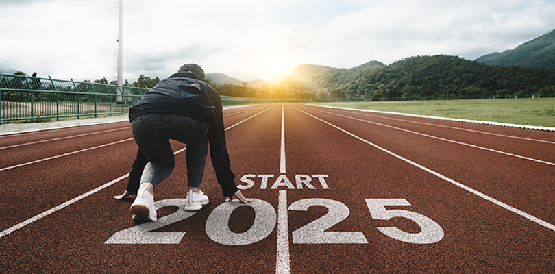 A runner about to run on an outdoor track with text underneath them that reads "Start 2025"