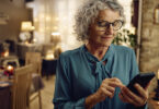 Senior woman using smartphone inside room.