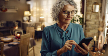 Senior woman using smartphone inside room.