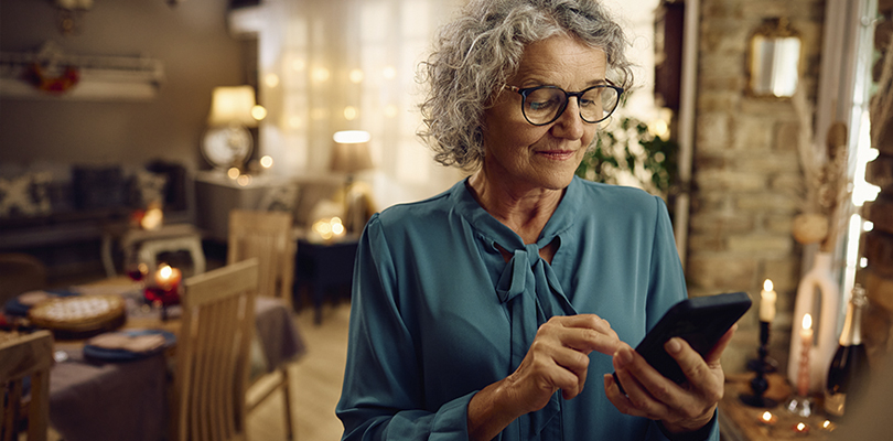 Senior woman using smartphone inside room.