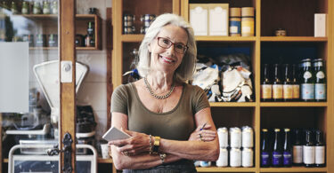 Senior woman holding pen and notepad in front of shelves of product