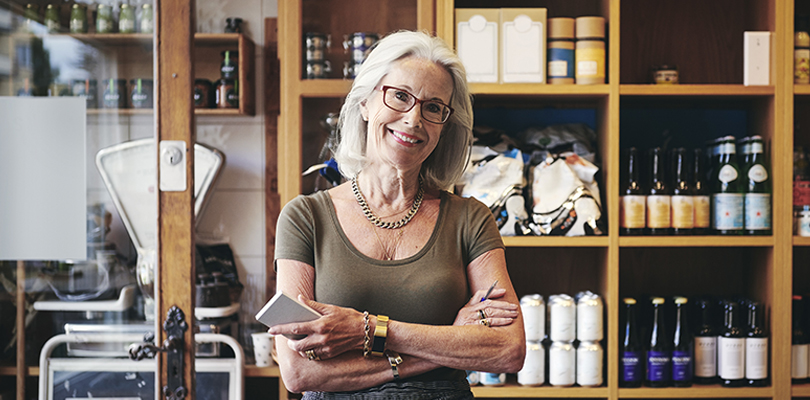 Senior woman holding pen and notepad in front of shelves of product