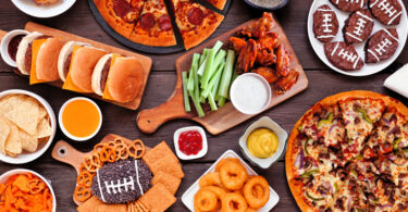 Super Bowl party food assortment, pizza, wings, celery sticks, chips, etc.