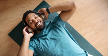 Man lying down on yoga mat with headphones on