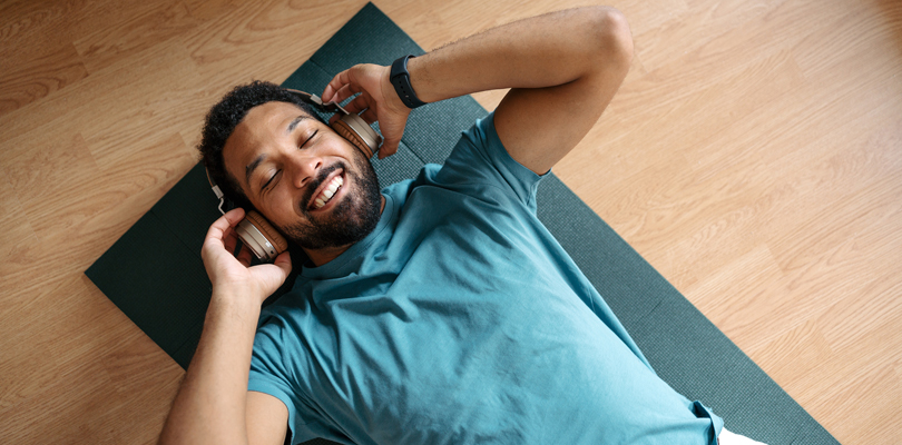 Man lying down on yoga mat with headphones on