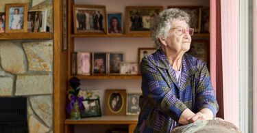 Elderly woman looking through a window