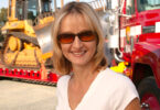 Heather Huerta smiling in front of 18-wheeler hauling a bulldozer