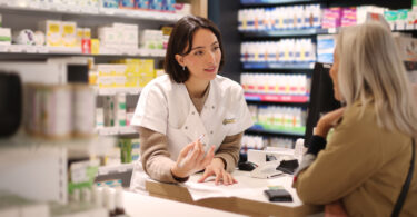 Pharmacist speaking to customer at checkout