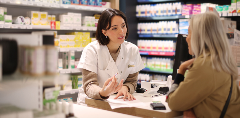 Pharmacist speaking to customer at checkout