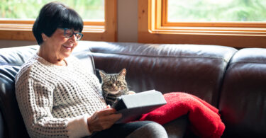 Senior woman using tablet with cat on her lap