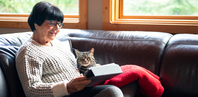 Senior woman using tablet with cat on her lap