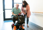 Man using motorized wheelchair talking to woman