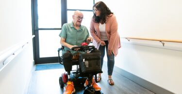 Man using motorized wheelchair talking to woman