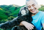 Senior woman smiling and hugging pet dog