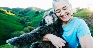 Senior woman smiling and hugging pet dog