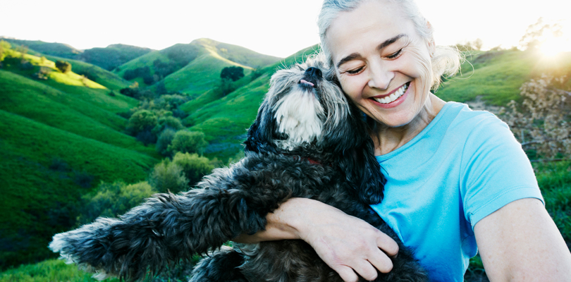 Senior woman smiling and hugging pet dog