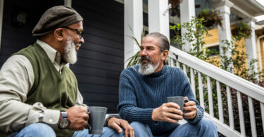 Two senior men sitting on porch talking to each other