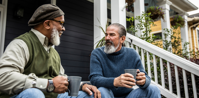 Two senior men sitting on porch talking to each other