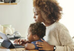 Mother working on tablet computer while her child is watching