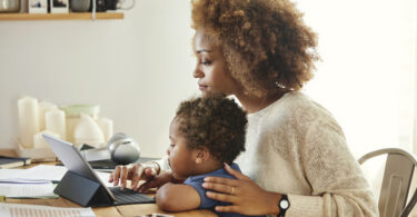 Mother working on tablet computer while her child is watching
